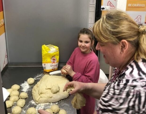 Дівчинка допомагає виготовляти гарячі пиріжки для військових на Солом‘янському ринку
