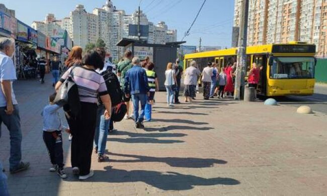 кияни чекають автобуси, стоячи у довжелезних чергах